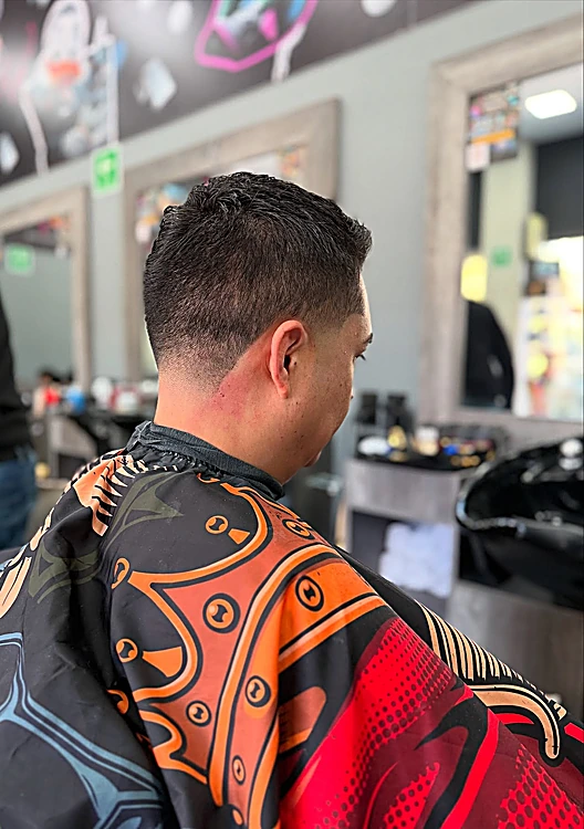 Corte clásico terminado visto desde la nuca, con capa estampada roja y naranja