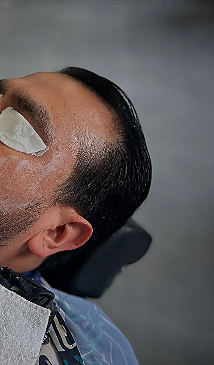 Cliente recostado con mascarilla facial y parche sobre el ojo