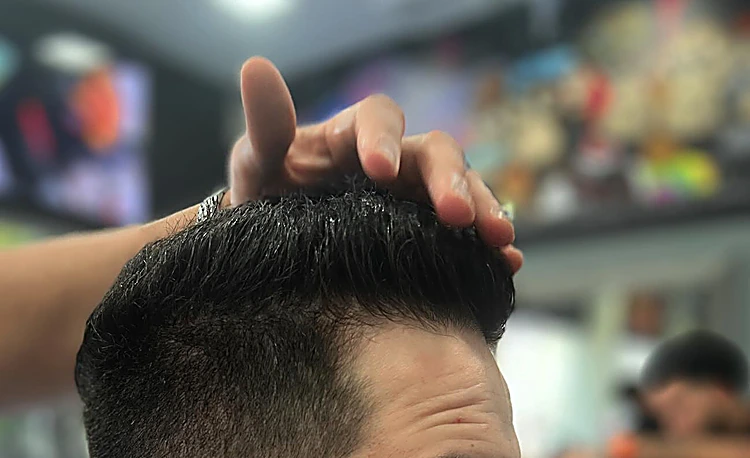 Barbero acomodando con la mano el peinado texturizado de un cliente